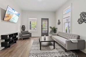 A modern living room with a grey sofa, a coffee table, and a flat-screen TV on the wall. - ⭐Modern 2 Bedroom Unit ⭐ Convenient ⭐ Near Downtown, Convention & Hospitals ⭐ (Indianapolis)