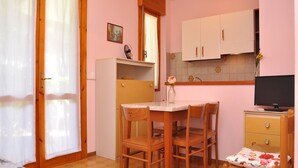 A compact room with a bed, a desk, a chair, a television, and a small kitchenette. - Cozy Flat in a Residence With 3 Pools - Beahost (San Michele al Tagliamento)