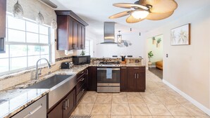 Una cocina moderna con alacenas de madera oscura, un horno de acero inoxidable y un amplio ventanal que aporta luz natural.