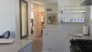 A modern kitchen with a gas stove, white cabinets, and a countertop. There is a hallway leading to a dining area with a chair and a table. - Urban Lifestyle, Lakes District of MPLS! Quiet Family Neighborhood, 1BR, 1BA (Minneapolis)