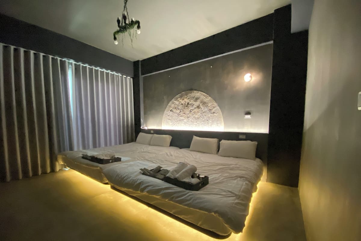 Un dormitorio moderno con una cama grande, una lámpara circular fijada a la pared y un candelabro.