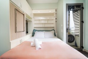 Ein Schlafzimmer mit Bett, Kleiderschrank und einer eingebauten Regalwand.