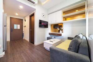Ein modernes Wohnzimmer mit einer Couch, einem Couchtisch und einem an der Wand befestigten Flachbildfernseher.