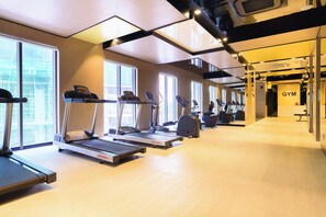 Ein Fitnessstudio mit Laufbändern, Crosstrainern und einem Bereich für Gewichte.