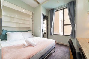 Ein Hotelzimmer mit einem Bett, einem Schreibtisch und einem Vorhangfenster.