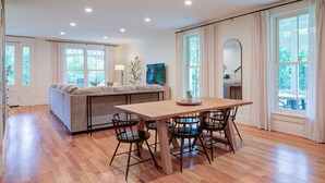 A spacious living area with a wooden dining table, four chairs, a sofa, and a large window. - LUX Waterside Retreat with Geo Dome + Outdoor Fire Table, Historic Property (Prospect)
