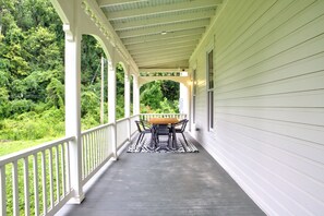 A covered porch with a table and chairs, surrounded by white railings and a view of greenery. - LUX Waterside Retreat with Geo Dome + Outdoor Fire Table, Historic Property (Prospect)