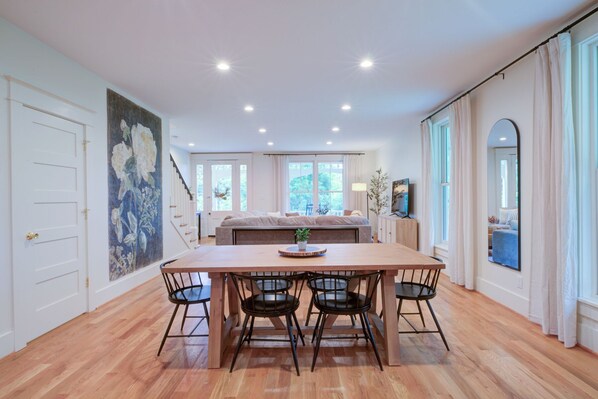 A spacious room with a wooden dining table and chairs, a large bed with a view to the outdoors, and a staircase leading to another level. - LUX Waterside Retreat with Geo Dome + Outdoor Fire Table, Historic Property (Prospect)