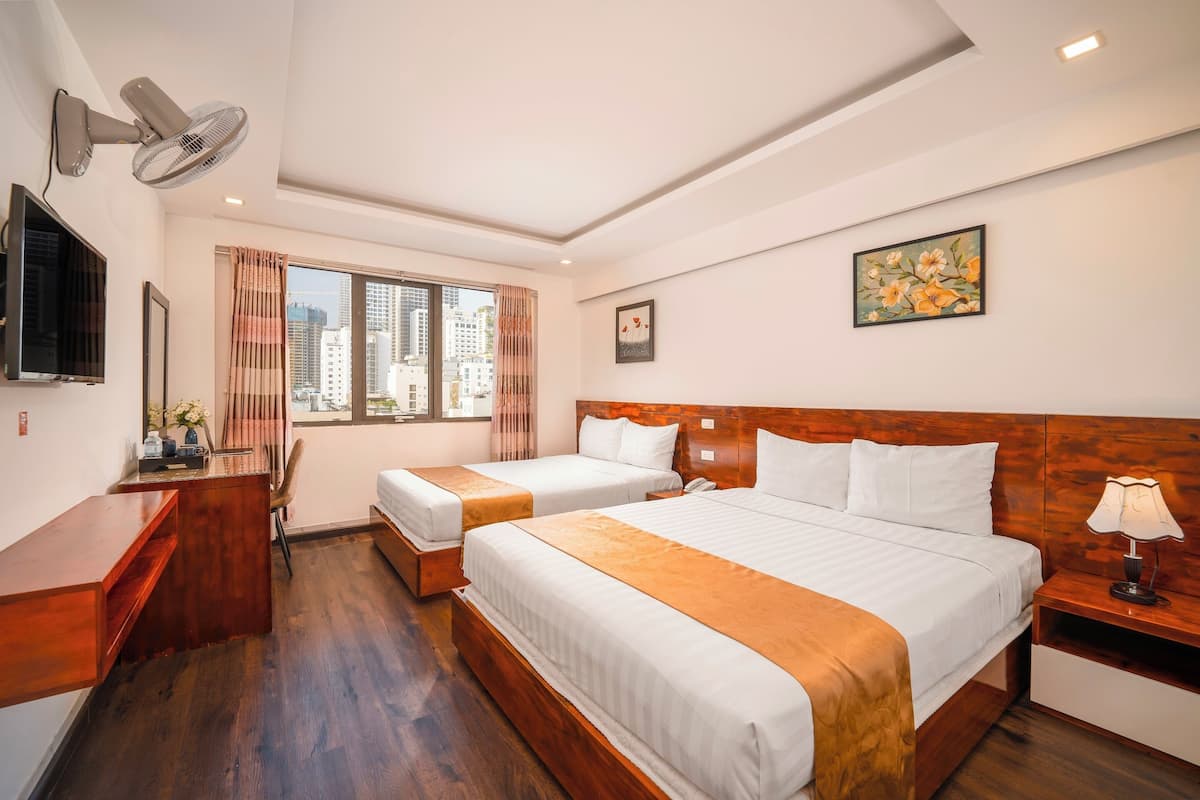 Une chambre d’hôtel avec deux lits, un bureau, une chaise, une télévision et une fenêtre avec des rideaux.