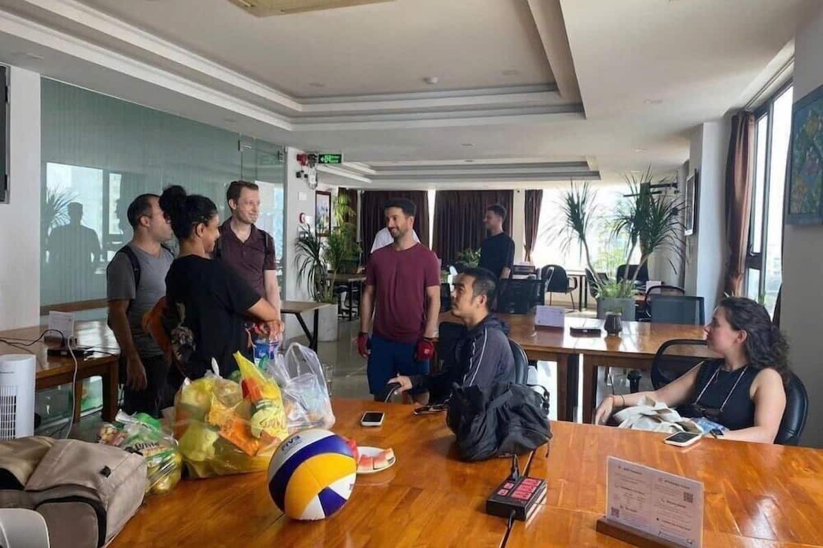 Une salle de conférence avec une table en bois, des chaises, un ballon de volley-ball et un ordinateur portable.