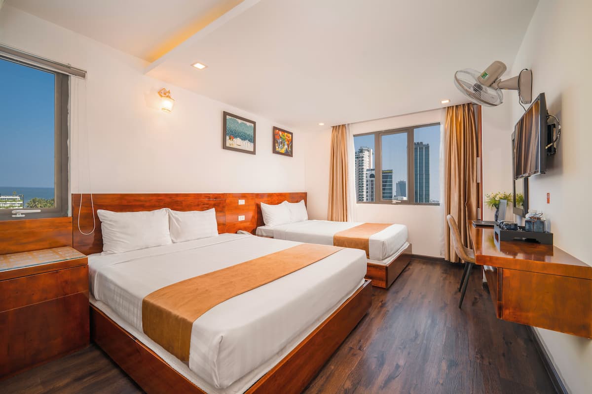 Une chambre d’hôtel avec deux lits, un bureau, une chaise, une télévision et une fenêtre donnant sur la ville.