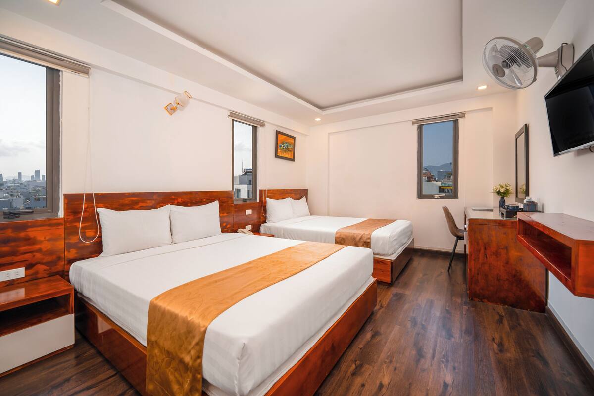 Une chambre d’hôtel avec deux lits, un bureau, une chaise, une télévision et une vue sur la ville.