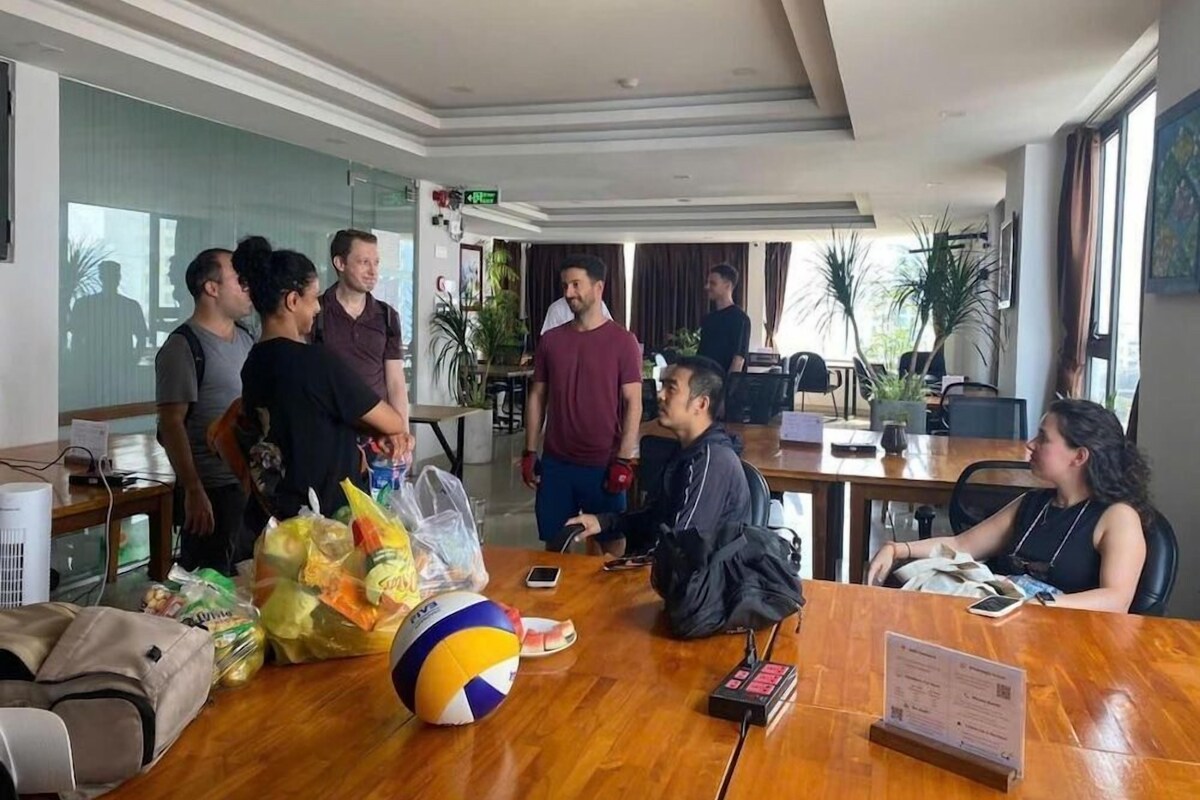 A conference room with a wooden table, chairs, a volleyball, and a laptop.