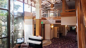 A spacious lobby with a piano, a television, and a seating area with a purple carpet. - Tabist Sakura no Yakata Hotel (Fuefuki)