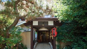 A traditional Japanese entrance with a wooden torii gate, a stone pathway, and lush greenery. - Tabist Sakura no Yakata Hotel (Fuefuki)