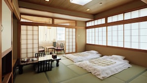 A traditional Japanese room with tatami flooring, two beds, a low table with a tea set, and sliding doors. - Tabist Sakura no Yakata Hotel (Fuefuki)