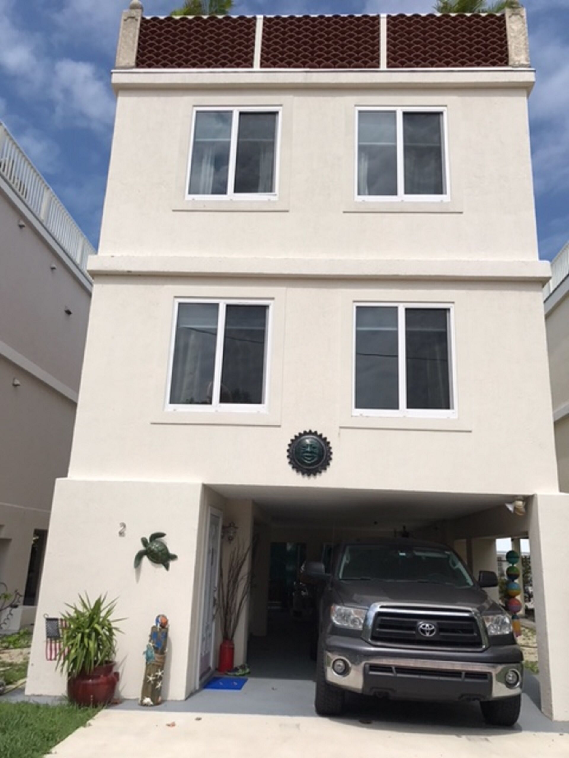 Un bâtiment à deux étages avec une entrée de garage, un pot de fleurs et un objet décoratif au rez-de-chaussée.