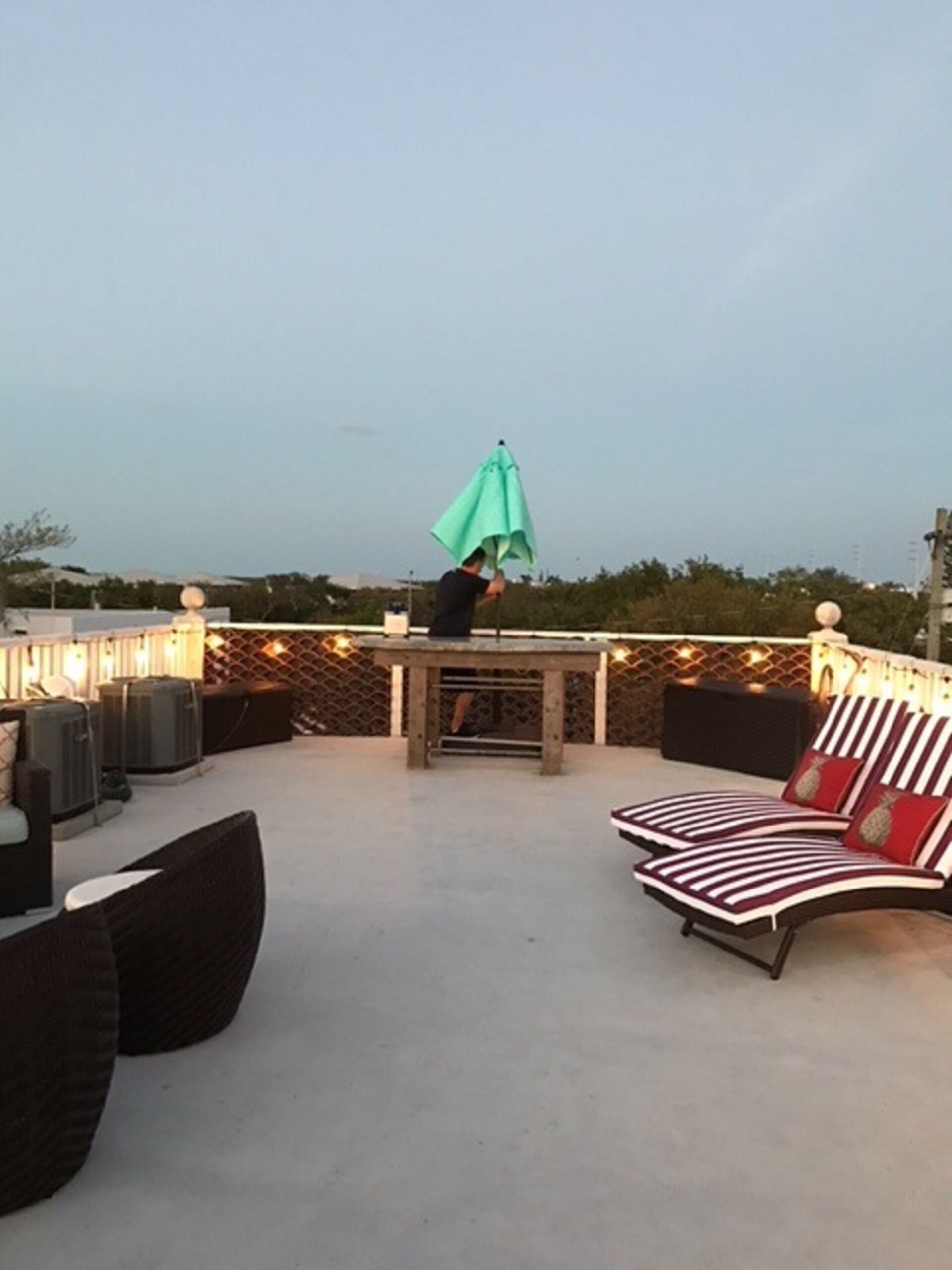 Une terrasse extérieure avec des sièges, une table et un parasol vert.