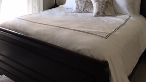 A bedroom with a bed, a ceiling fan, a window with curtains, and a bedside lamp.
