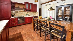 A kitchen with red cabinets, a tiled backsplash, a wooden dining table, and hanging pendant lights. - Jurinea in Vi Njan With 4 Bedrooms and 2 Bathrooms (Visnjan)