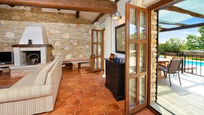 A cozy living area with a stone fireplace, a sofa, and a dining table with chairs. - Jurinea in Vi Njan With 4 Bedrooms and 2 Bathrooms (Visnjan)