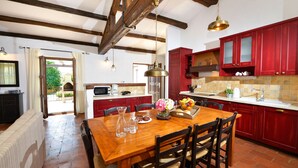 A spacious kitchen with a wooden dining table, red cabinets, and a view to the outside. - Jurinea in Vi Njan With 4 Bedrooms and 2 Bathrooms (Visnjan)