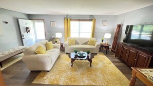 A living room with a sofa, a coffee table, and a television. There is a door and a window with curtains. - Beautiful 3br, 1.5 bath townhouse centrally located in the heart of Milwaukee. (Milwaukee)