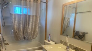 A bathroom with a bathtub, toilet, sink, and a showerhead.