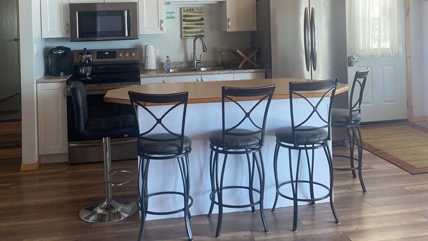 A modern kitchen with white cabinets, stainless steel appliances, and a wooden ceiling.