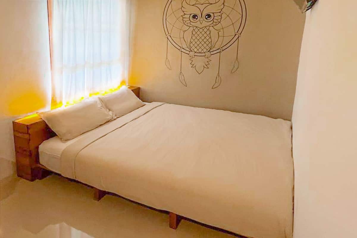 A single bed in a room with a white wall and a dreamcatcher decoration.