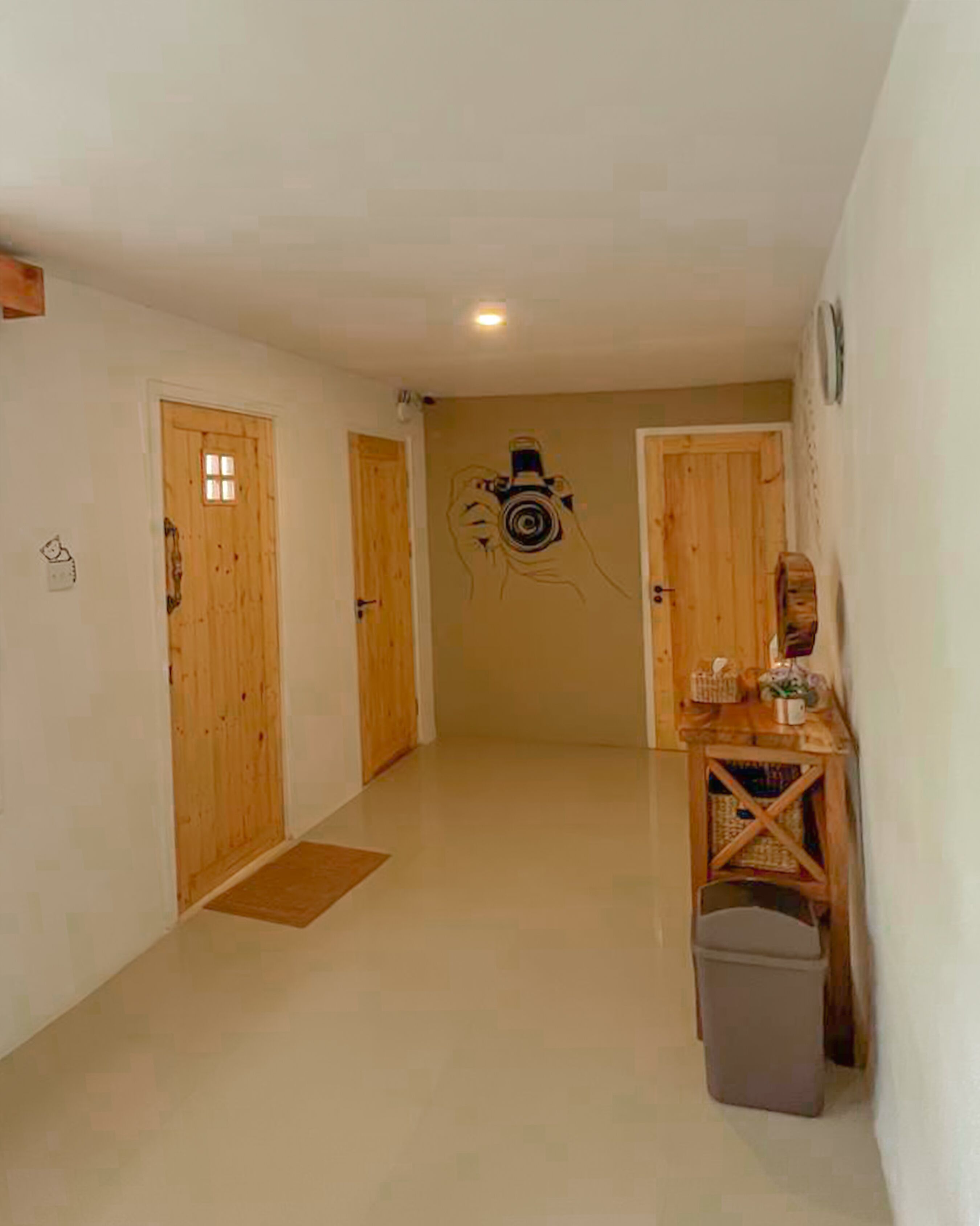 Ein Korridor mit Holztüren, einem kleinen Tisch und einem Mülleimer sowie einer an der Wand befestigten Kamera.
