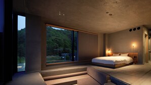 Un dormitorio moderno con un ventanal grande, una cama y una escalera que lleva a un espacio al aire libre.