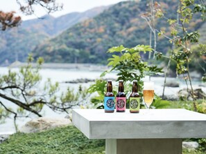Una mesa con cuatro botellas de cerveza y una jarra frente a un lago y montañas panorámicos.