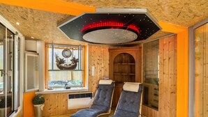 Una habitación con dos sillones reclinables, techo de madera, un ventanal grande y un adorno en la pared.