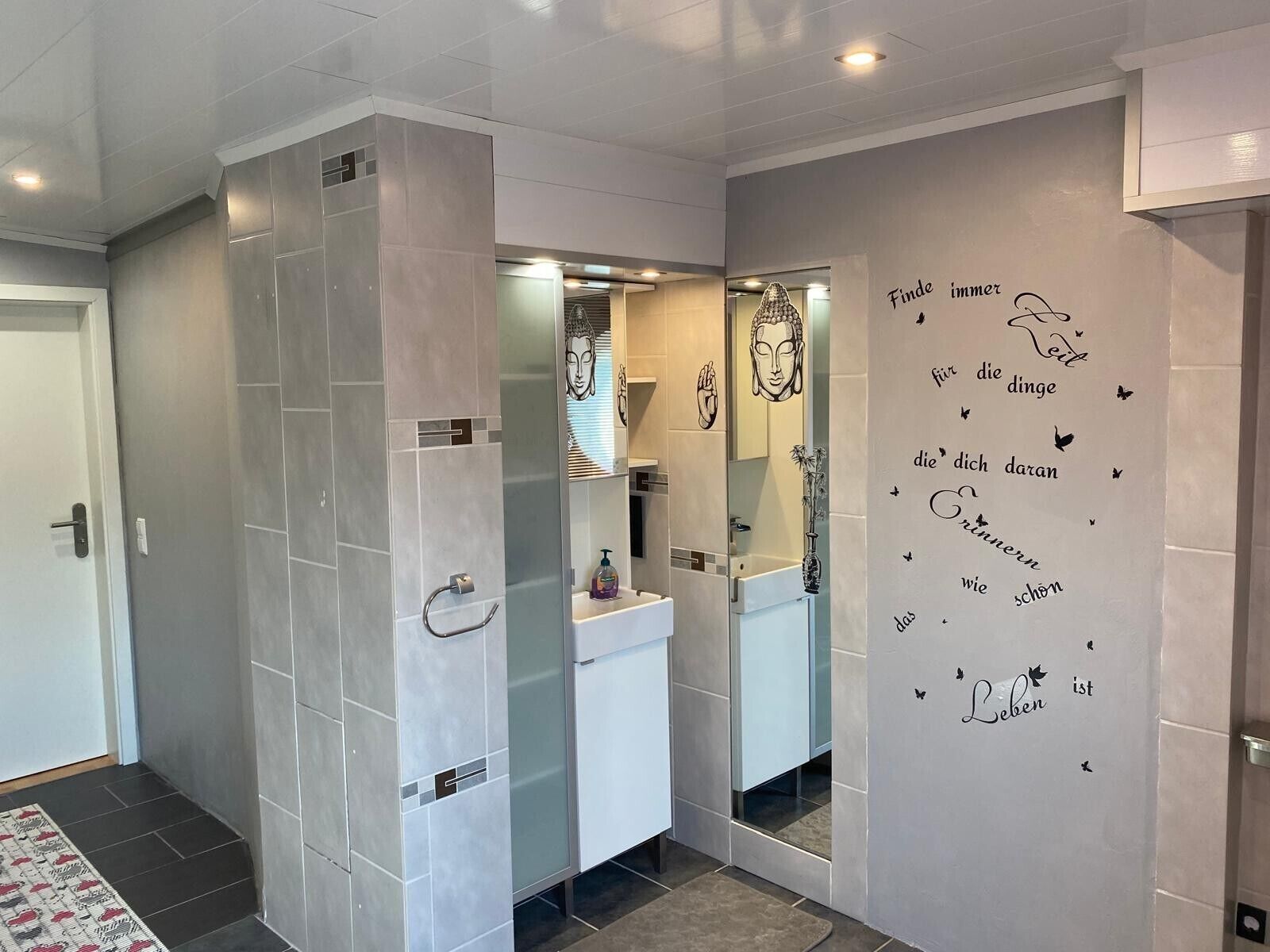 A modern bathroom with a glass partition, a white sink, and a mirror.