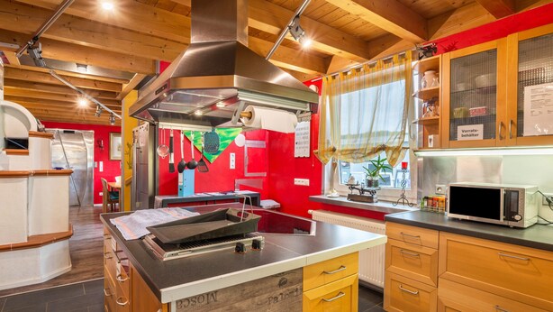 Una cocina con armarios de madera, una campana extractora de acero inoxidable y un microondas.