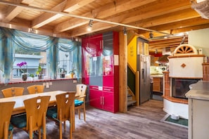 Interior de madeira com área de refeições, um armário vermelho e uma cozinha com fogão.