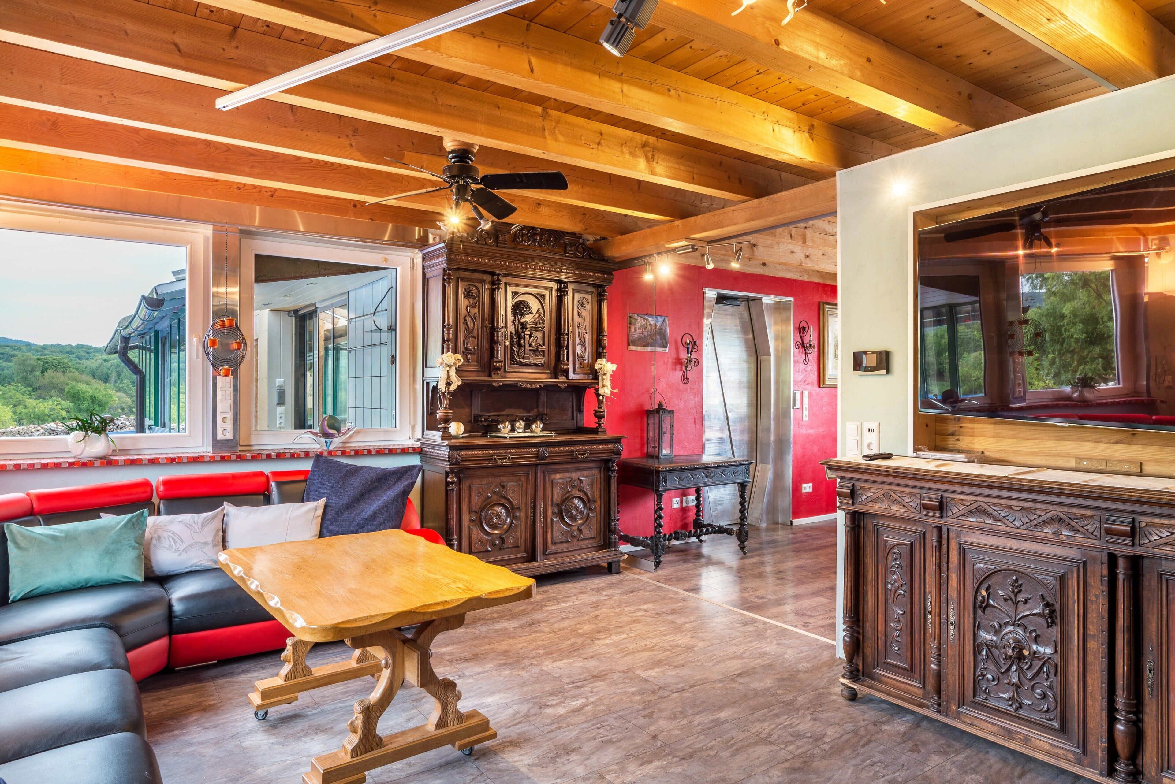 Een gezellige woonkamer met een houten plafond, een bank, een tafel en een open haard.
