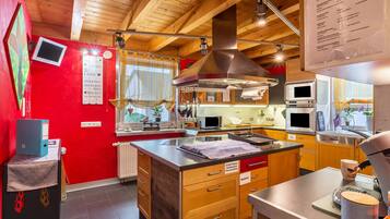 A modern kitchen with wooden cabinets, stainless steel appliances, and a red accent wall.