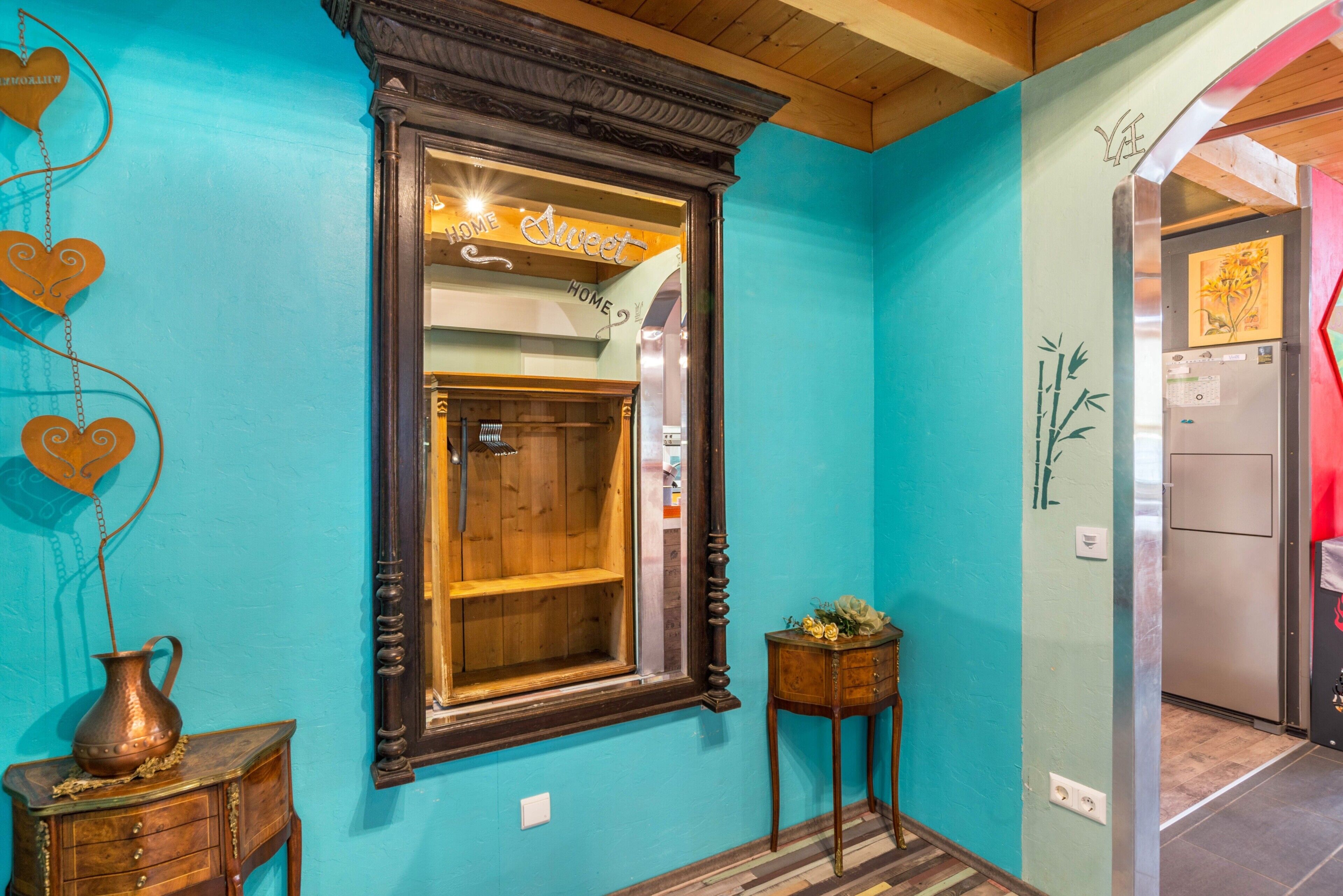 A room with a large mirror, a wooden cabinet, and a small table with a vase.