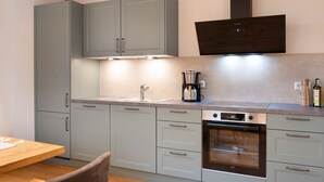 A kitchen with grey cabinets, a built-in oven, and a coffee maker. - Holiday Apartment "Morgentau" with Private Terrace & Wi-Fi (Heiligenberg)