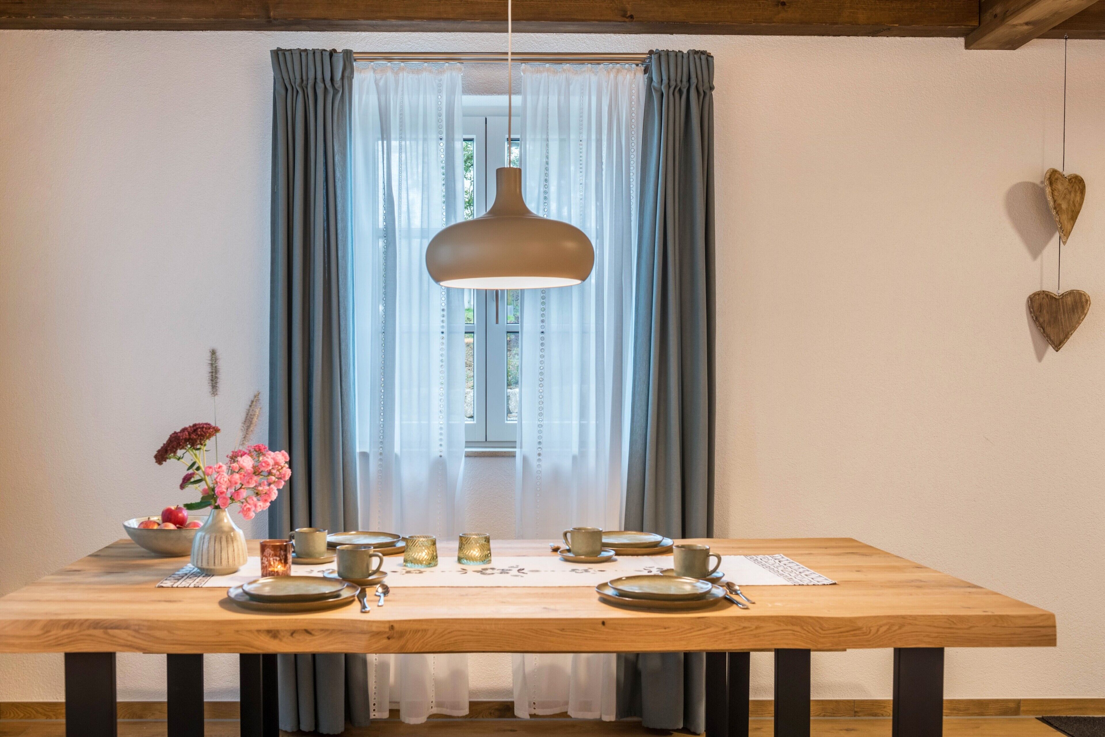A dining table set with plates, cups, and a vase of flowers.