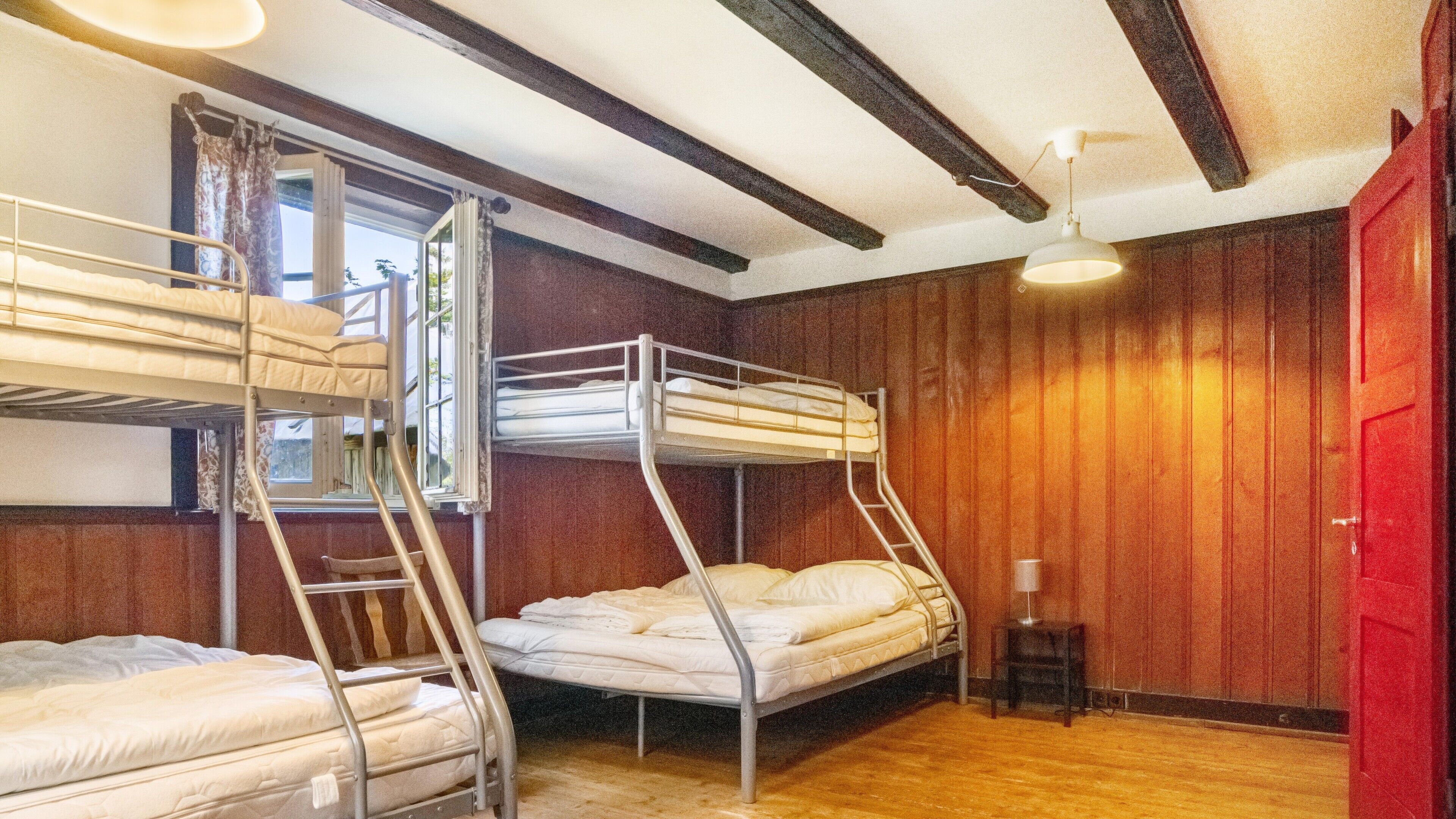 Ein Schlafzimmer mit Etagenbetten, Holzwänden und einer roten Tür.