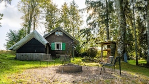 A rustic cabin with a wooden exterior, a small porch, and a fire pit in the yard.