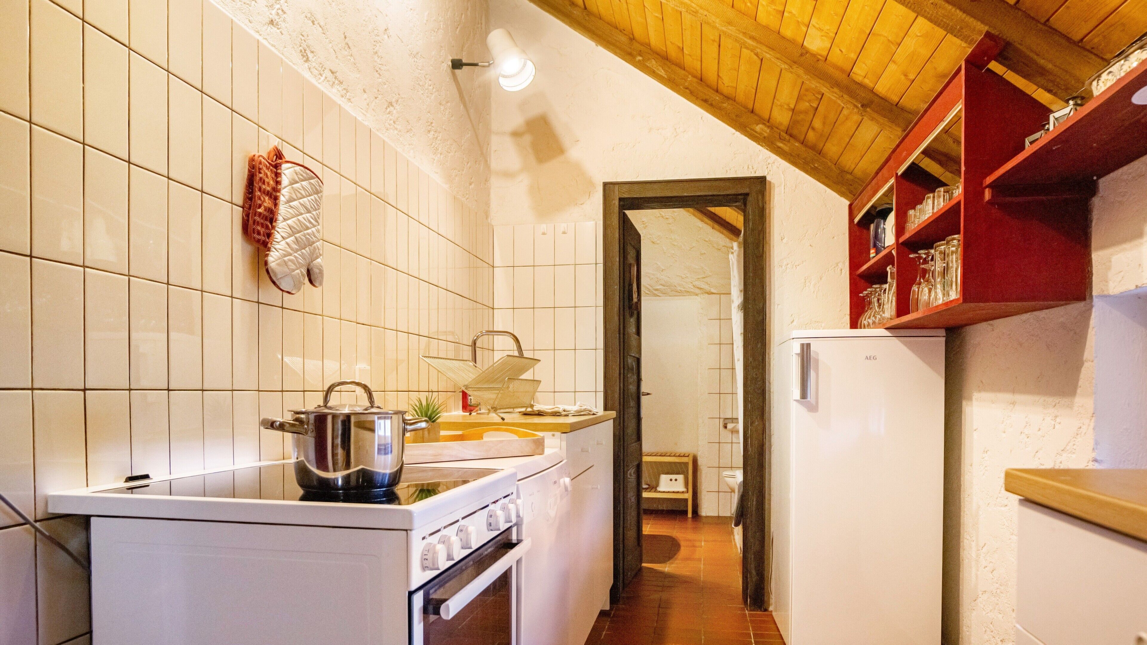 Uma cozinha com azulejos brancos, fogão, forno e geladeira.