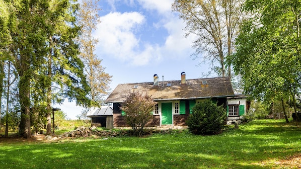 A house with a green door, surrounded by trees and a grassy yard.