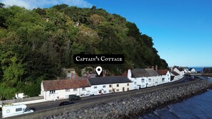 A coastal building named Captain's Cottage with a white facade, located beside a rocky shoreline with a view of the sea. - Captain's Cottage, Minehead (Minehead)