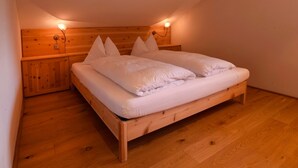 A room with a wooden bed, two bedside lamps, and a wooden headboard. - Holiday Apartment "Rosengartnerhof Maultasch" with Mountain View, Shared Pool & Wi-Fi (Terlan)