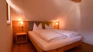 Un dormitorio con una cama de madera, dos mesitas de noche e iluminación en la pared.