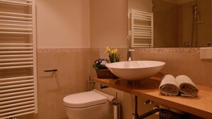 Un baño con inodoro, lavabo, espejo y toallero.